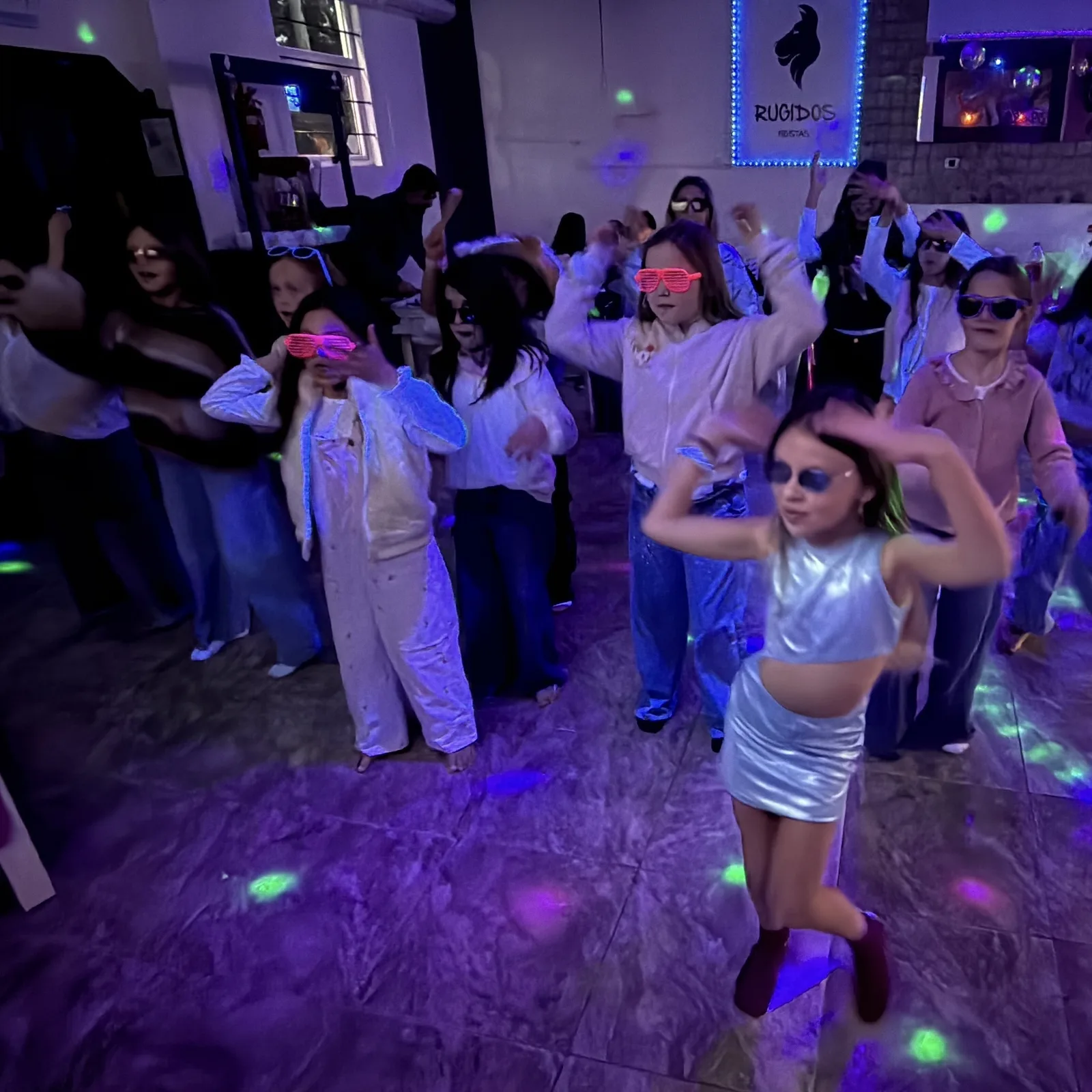 Chicos bailando con anteojos flúor en la fiesta de Rugidos